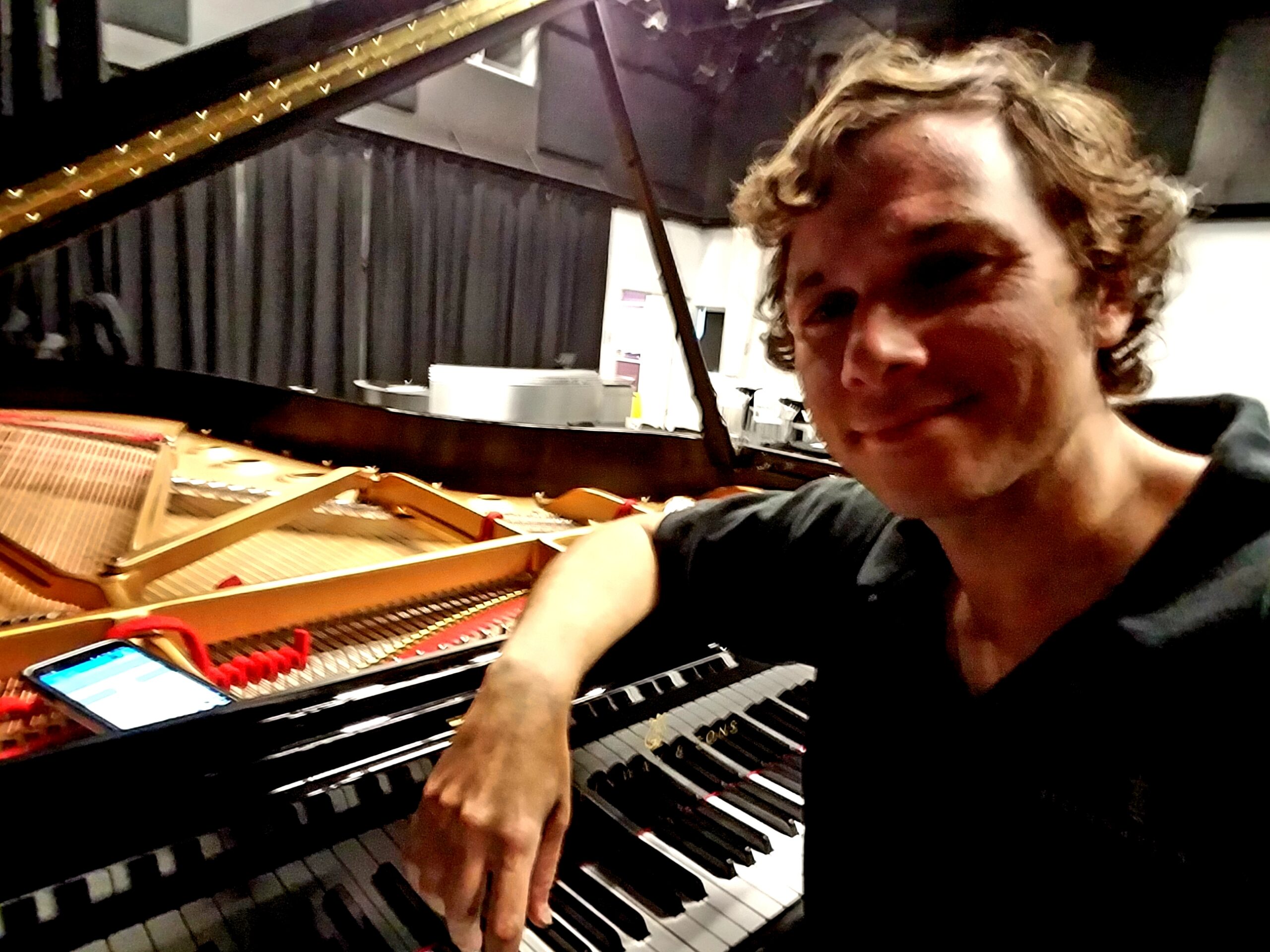 Piano technician seated at a grand piano keyboard in a studio setting